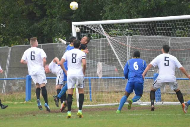 Simon Lehkyj punches the ball away under pressure. Raynes Park Vale v Haywards Heath Town. Picture by Grahame Lehkyj
