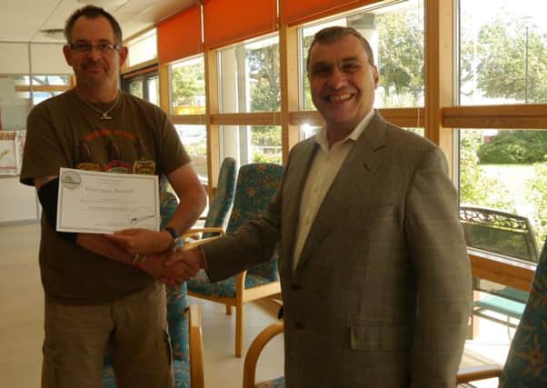 Nathan Dodsworth who is receiving treatment at the Queen Alexandra Hospital Home in Worthing receives his cheque from The CiaO Foundation from Geoffrey Barber