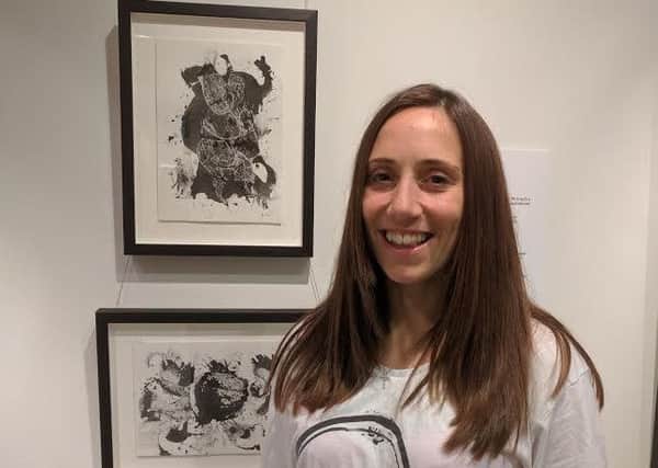 Dannielle Hodson next to her artworks Battle of the Dresses (portrait) and Cabaret Monkey (landscape)