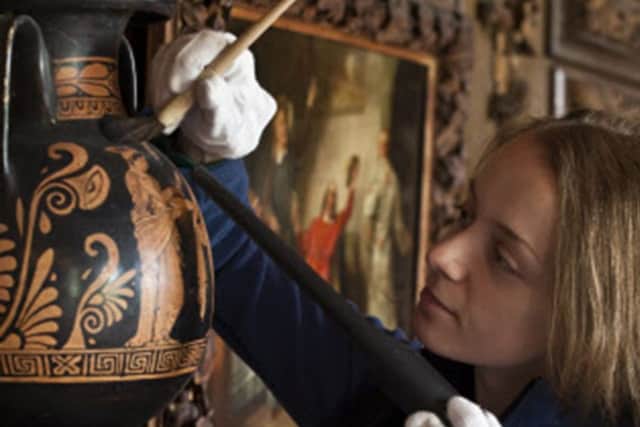 Conservation staff cleaning a vase at Petworth House