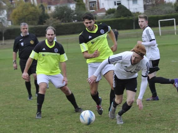 Bexhill United midfielder Wayne Giles seeks to evade the clutches of two St Francis Rangers opponents.