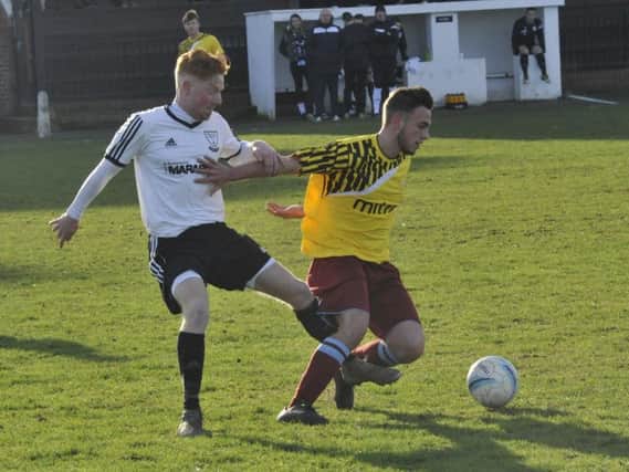 Little Common midfielder Harry Saville holds off Bexhill United's Wayne Giles. Picture by Simon Newstead