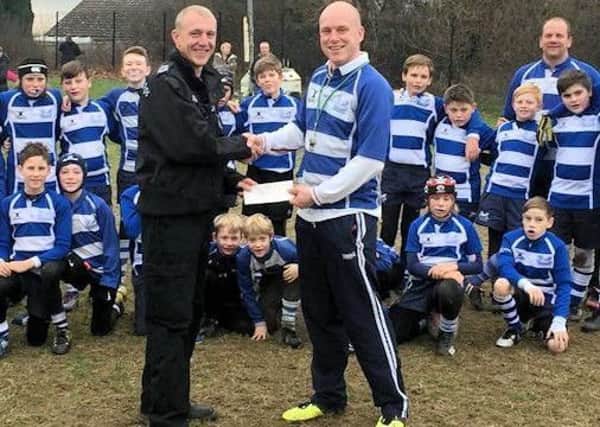 Sergeant Steven Prince handing cheque to Hastings and Bexhill Rugby Club under-11s coach Ben Westgate. Photo courtesy of Sussex Police SUS-170401-182409001