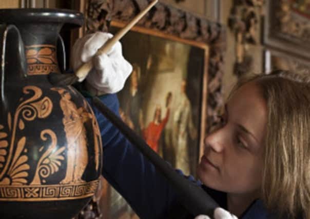 Conservation staff cleaning a vase at Petworth House,