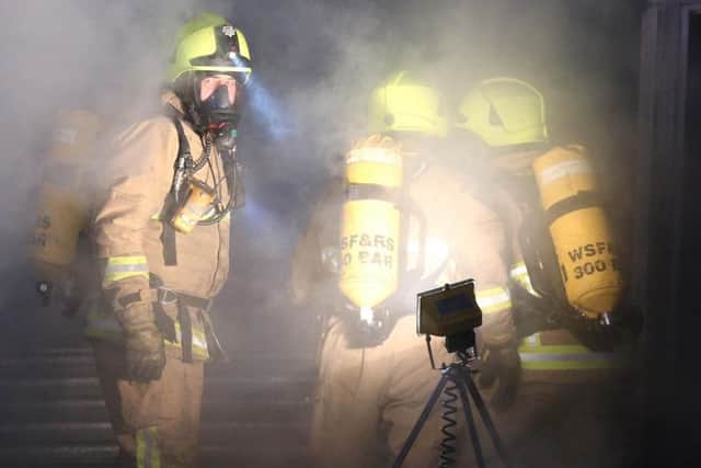 Fire crews wearing breathing equipment fight back the flames. Photo by Eddie Mitchell