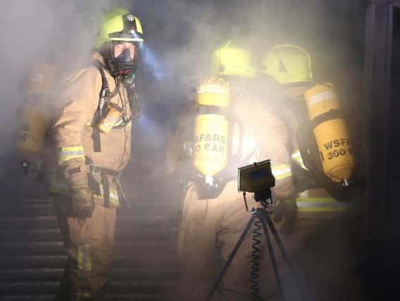 Fire crews wearing breathing equipment fight back the flames. Photo by Eddie Mitchell