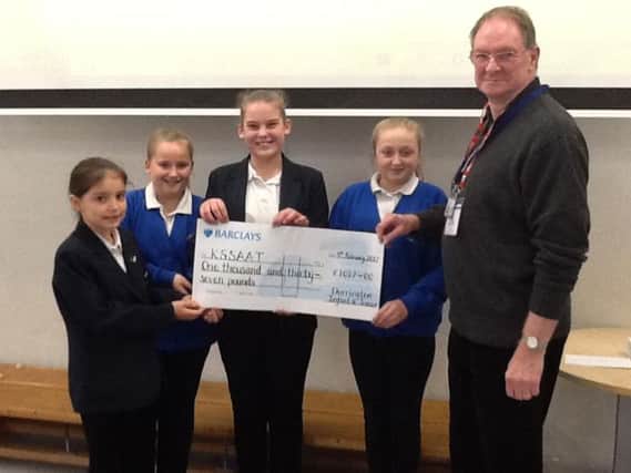 Derek Richardson of the Kent, Surrey and Sussex Air Ambulance Trust, receives a cheque from Year 6 children at Durrington Infant and Junior School