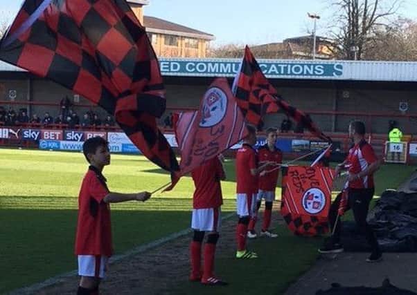 Kids from Maidenbower Junior School waving flags to welcome the players on to the pitch at Crawley Town v Morecambe. Picture by Steve Herbert SUS-170220-151440002