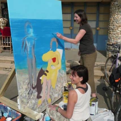 Nadia and Vanessa painting the commissioned cutout outside Creative Wave's beach hut