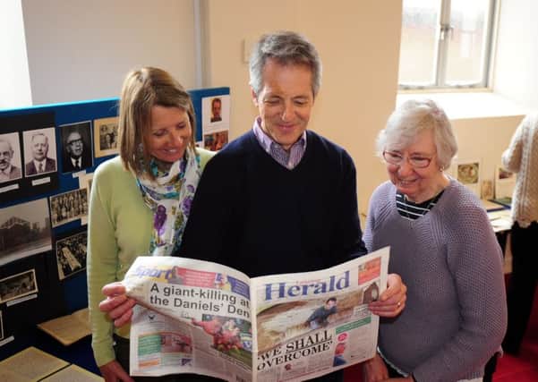 Pastor John Woods, centre, with his wife Anne, left, and Janet Bradley looking  at an archived copy of the Herald. Picture: Kate Shemilt ks170135-1