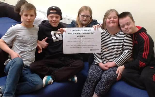Students with Down Syndrome hold up their coffee afternoon invitation