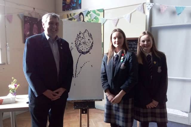 Year-ten students Izzy Saunders and Charlie Cogger with Rotarian Paul Hickson by a purple crocus painted with fingerprints at the celebration