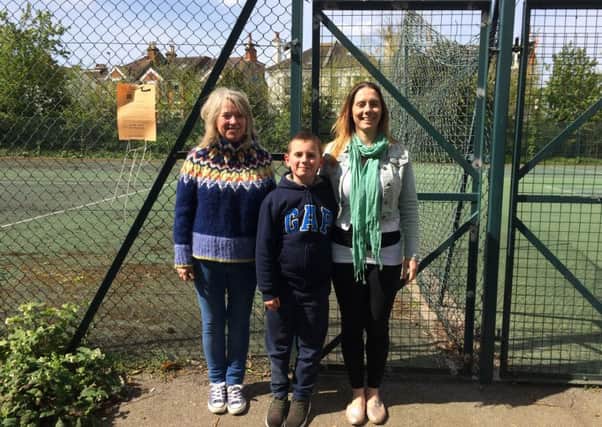 Liz English, Gemma Spicer and Reece Spicer next to the public notice on the tennis courts
