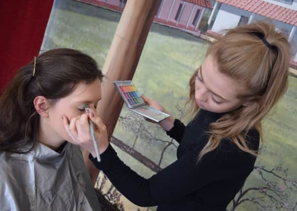Student Katie Sheat applies eye make up to a member of staff at Fishbourne Roman Palace