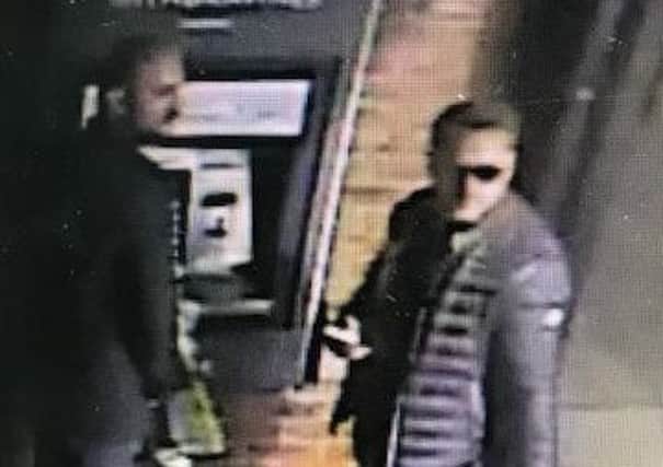 CCTV image of two men suspected to have been involved in the theft of a woman's cards and withdrawing large sums from her accounts.