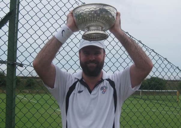 Mark Hadley lifts the men's singles trophy at last year's tournament.