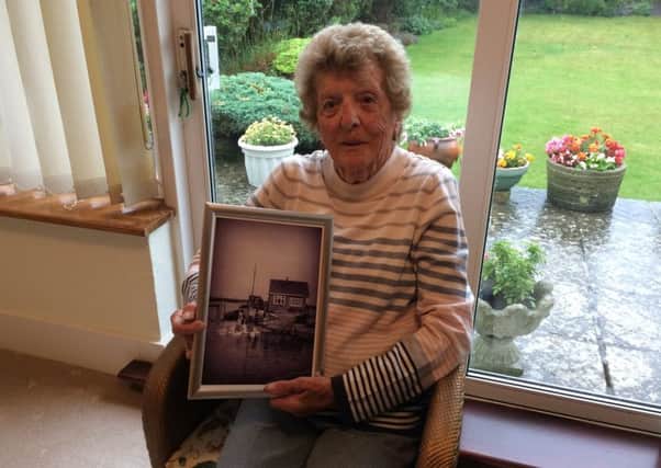 Peggy McCulloch at her home on Shoreham Beach, with a photo of the home she grew up in, also on Shoreham Beach