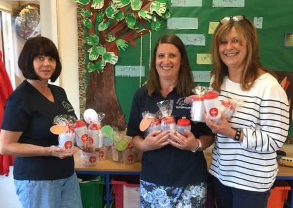 From left: Bev Fuller and Jenny Emerson, of Fishbourne Pre-School, receiving the bottles from Mandy Hine, of Message-on-a-Bottle