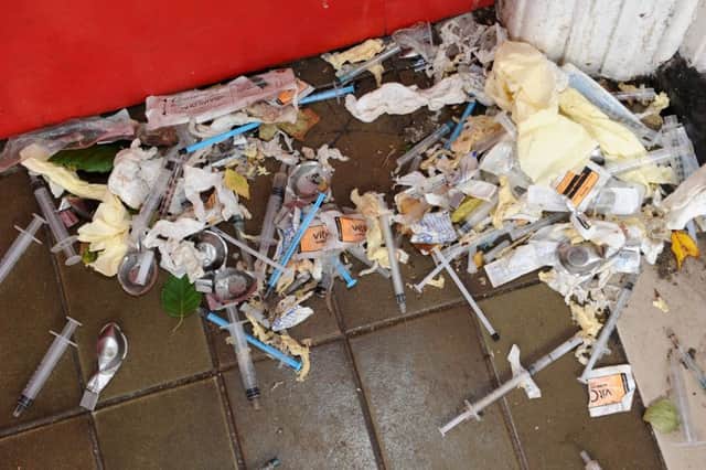 The pile of discarded used needles and drug paraphernalia in a town centre doorway