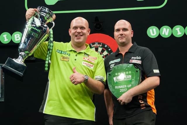 St Leonards darts star Rob Cross (right) clutches the runner-up prize alongside winner Michael van Gerwen at the Unibet European Championship. Picture courtesy Kelly Deckers
