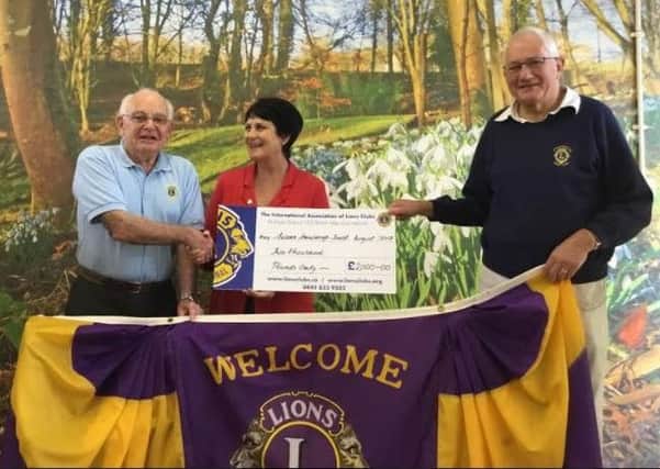 Di receiving the cheque from, Lions president John Taylor (left) and Lions club member David Cook