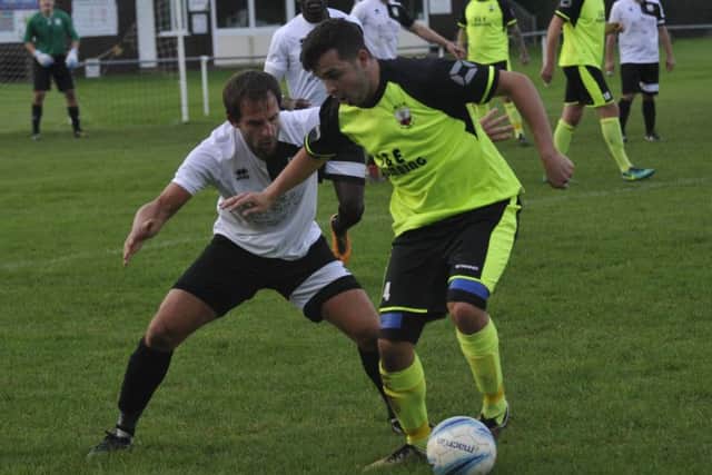 Bexhill United scorer Chris Rea blocks the path of a Wick opponent.
